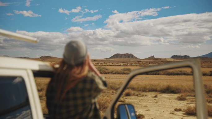 一名女子在摩洛哥某地用双筒望远镜观察沙漠和山脉
