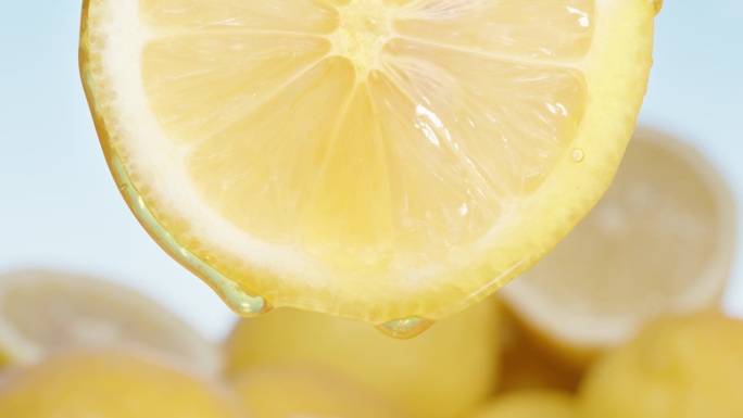蜂蜜从一片柠檬上滴下来，旁边是一堆柠檬片。特写镜头。