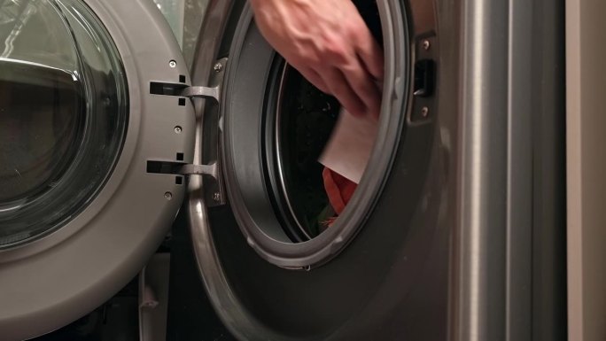 男子用手把吸色片放在洗衣机里