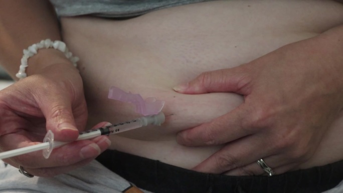 一名妇女在家里为她的体外受精胚胎移植做注射准备的特写