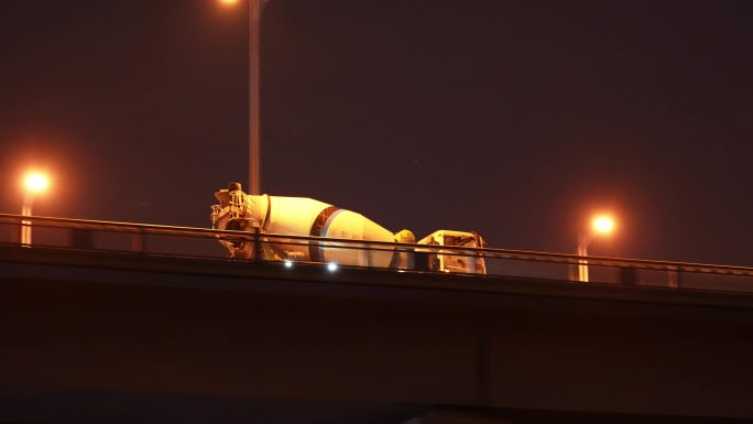 夜晚桥上经过的水泥搅拌车工程罐车