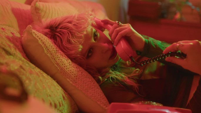 浪漫女孩在霓虹灯下的床上用90年代美学手机聊天