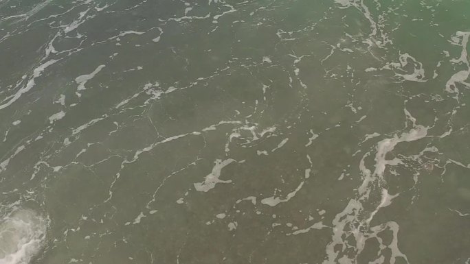 平滑的电影架空，海浪在浅水中撞击卵石海滩。在菲律宾拍摄。