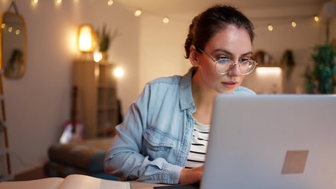现代年轻女性在家里学习，同时使用笔记本电脑