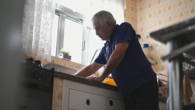 体弱多病、情绪低落的老人在厨房水槽旁的家中感到身体不适。与年老和精神疾病作斗争的老年人