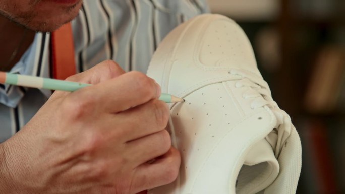 男设计师在白色运动鞋上画草图