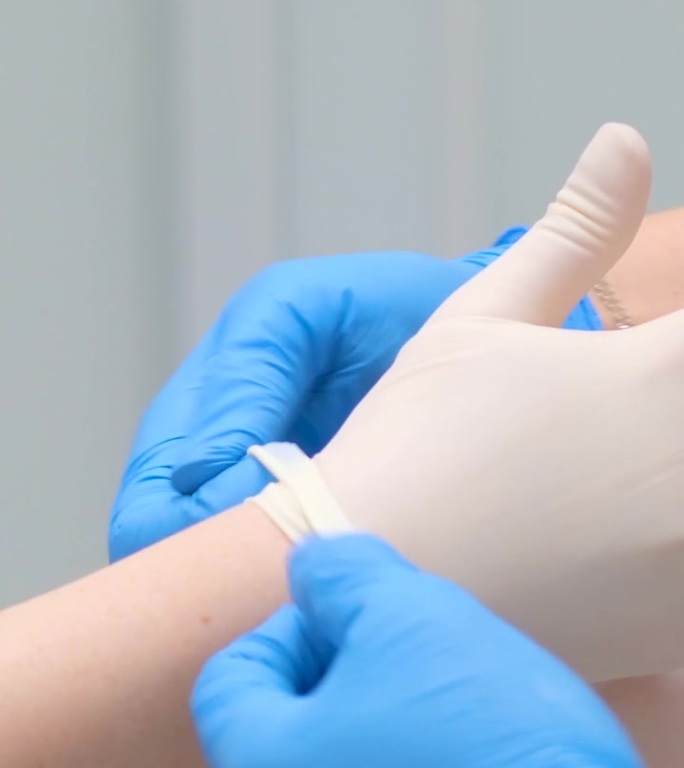 护士给医生戴上可洗手术手套个人防护用品乙烯基一次性手套防止感染冠状病毒防护趋势是COVID-19。