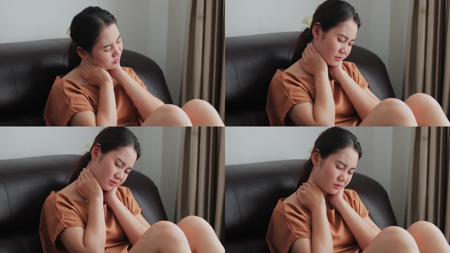 疲惫的亚洲年轻女子因剧烈疼痛而用手摸自己的脖子。在家的沙发上，肌肉遭受纤维肌痛的折磨。