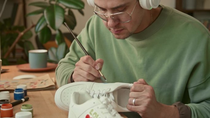 戴着耳机的男设计师在运动鞋上画画