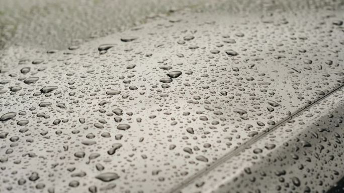 阴雨天，雨滴落在一辆黑色跑车上。