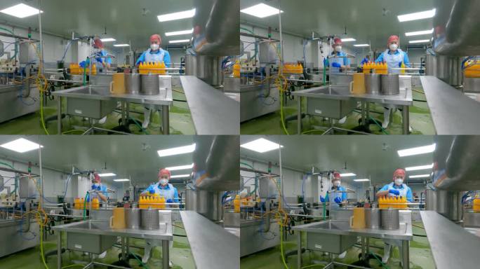 亚洲华人男果汁厂工人在生产线上封橙汁瓶盖