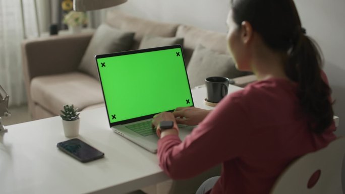 女性在家里使用绿屏空白的笔记本电脑