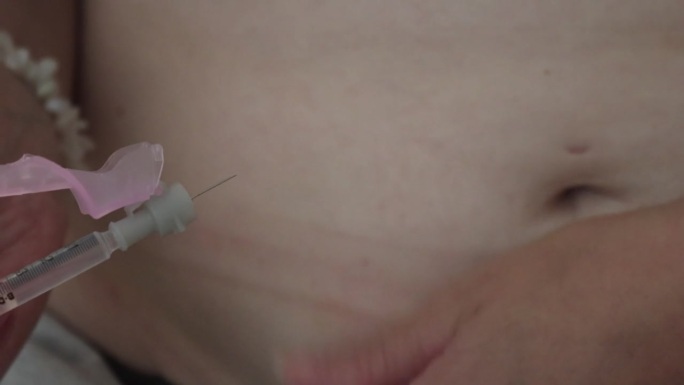 一名妇女在家里为她的体外受精胚胎移植做注射准备的特写