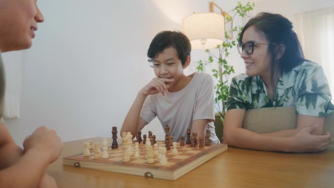 快乐的一家人在假期一起在家里下棋。