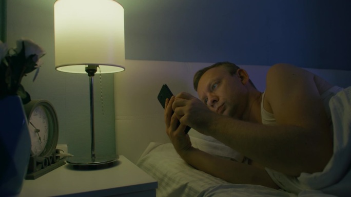 男人半夜醒来，躺在床上刷手机应用