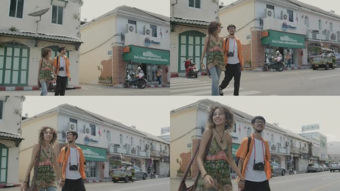 甜蜜的情侣在曼谷旅行。他们手牵着手一起走在人行横道上，背景是古色古香的建筑。