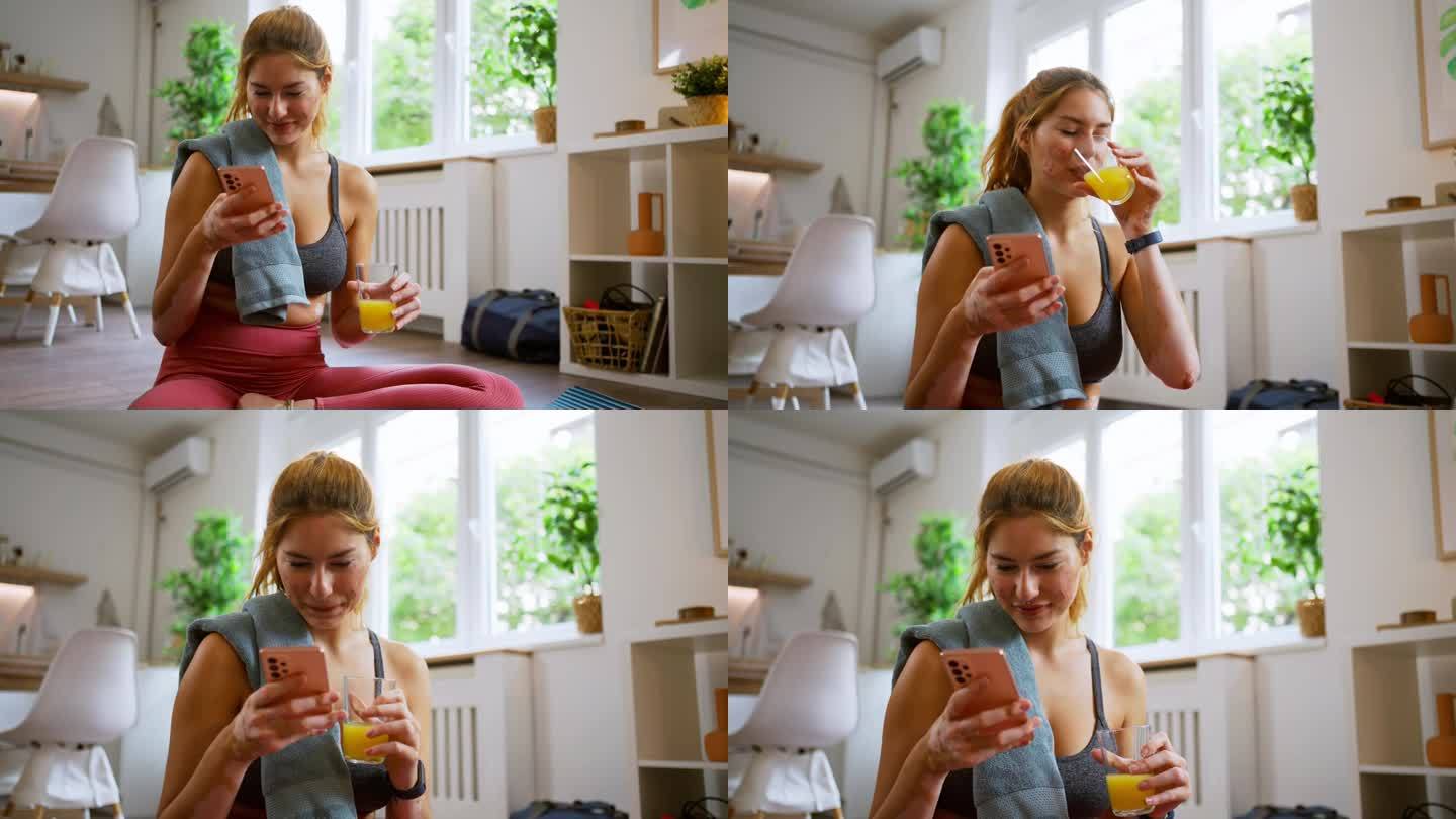 患有白癜风的高加索妇女，在家锻炼结束后，一边用手机一边喝橙汁