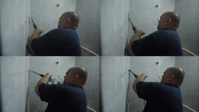 男杂工，用冲击钻拆除客户浴室的瓷砖