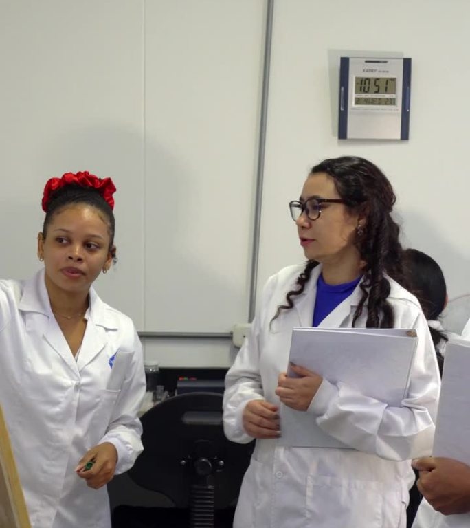 三个拉丁裔研究人员站在白板前用记号笔讨论一个项目