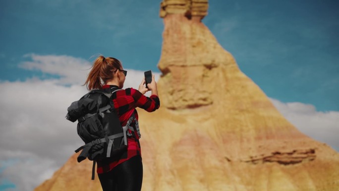 女徒步旅行者用手机拍摄砂岩岩层