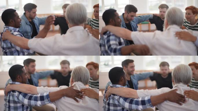 在集体治疗过程中，成熟的男性治疗师和一群多年龄的患者围成一圈坐在一起，把手放在对方的肩膀上
