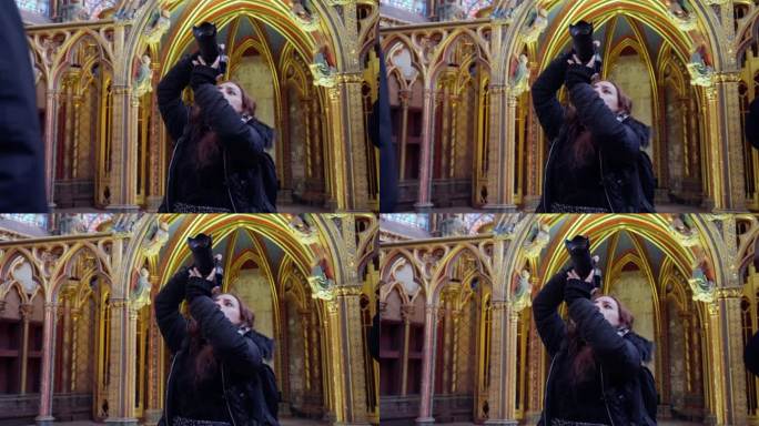 侧视图，年轻的西班牙裔妇女穿着温暖的夹克，用专业相机拍摄雄伟的哥特式教堂圣礼拜堂内部，法国巴黎
