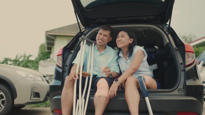 愉快的残疾亚洲夫妇谈话和微笑。后备箱里的爱。