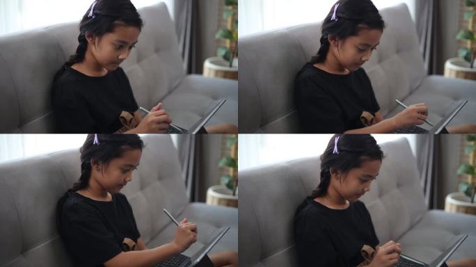 快乐女孩在家里用笔记本电脑在线学习英语。
