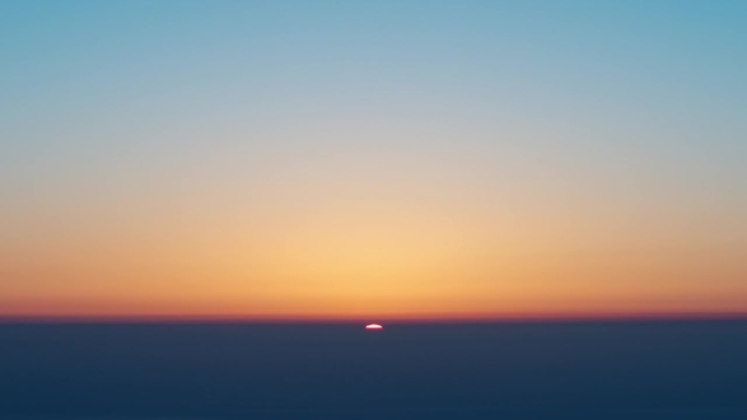 从山顶看日出的4K延时镜头，太阳从云层地平线升起，金色的太阳与温暖的云和蓝天背景。