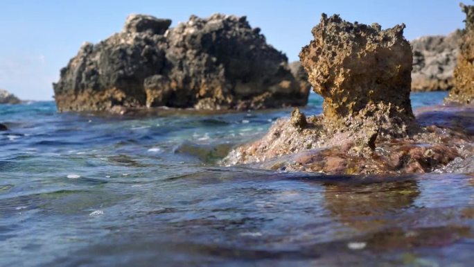 希腊科孚岛Limni海滩的海景。阳光照射到海面上可见的尖锐岩石，相机潜入水下-可见覆盖着藻类和水生植