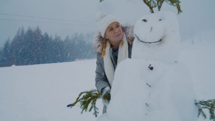 一个女人抱着她刚堆好的雪人
