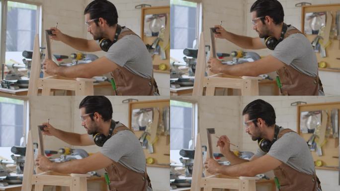 家具作坊的小企业主用笔记本电脑检查新木椅的图纸设计，帅气的木匠开始组装木椅