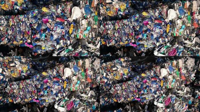 在露天的废物回收厂，多个立方体压缩的彩色塑料垃圾