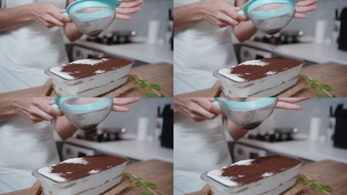 一名糕点师通过细筛将可可粉洒在提拉米苏蛋糕上，慢动作。