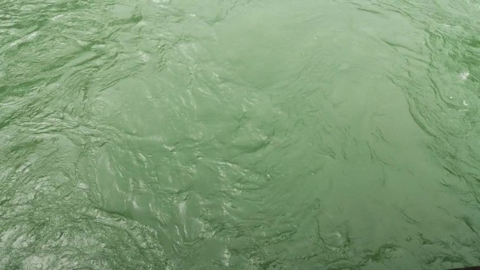 从上面看河。视频作为背景。高角度看绿色的水和波浪。平静的海浪和水，4k慢动作镜头。