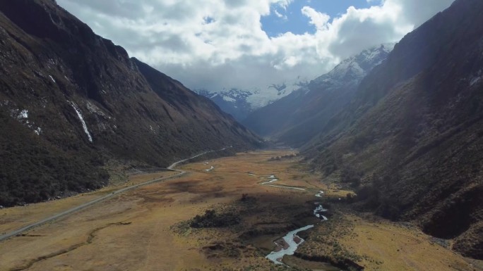 摄像机升起，小河和薄薄的柏油路蜿蜒穿过山谷，内华达马特奥山脉的山峰在阴天的远处有冰川