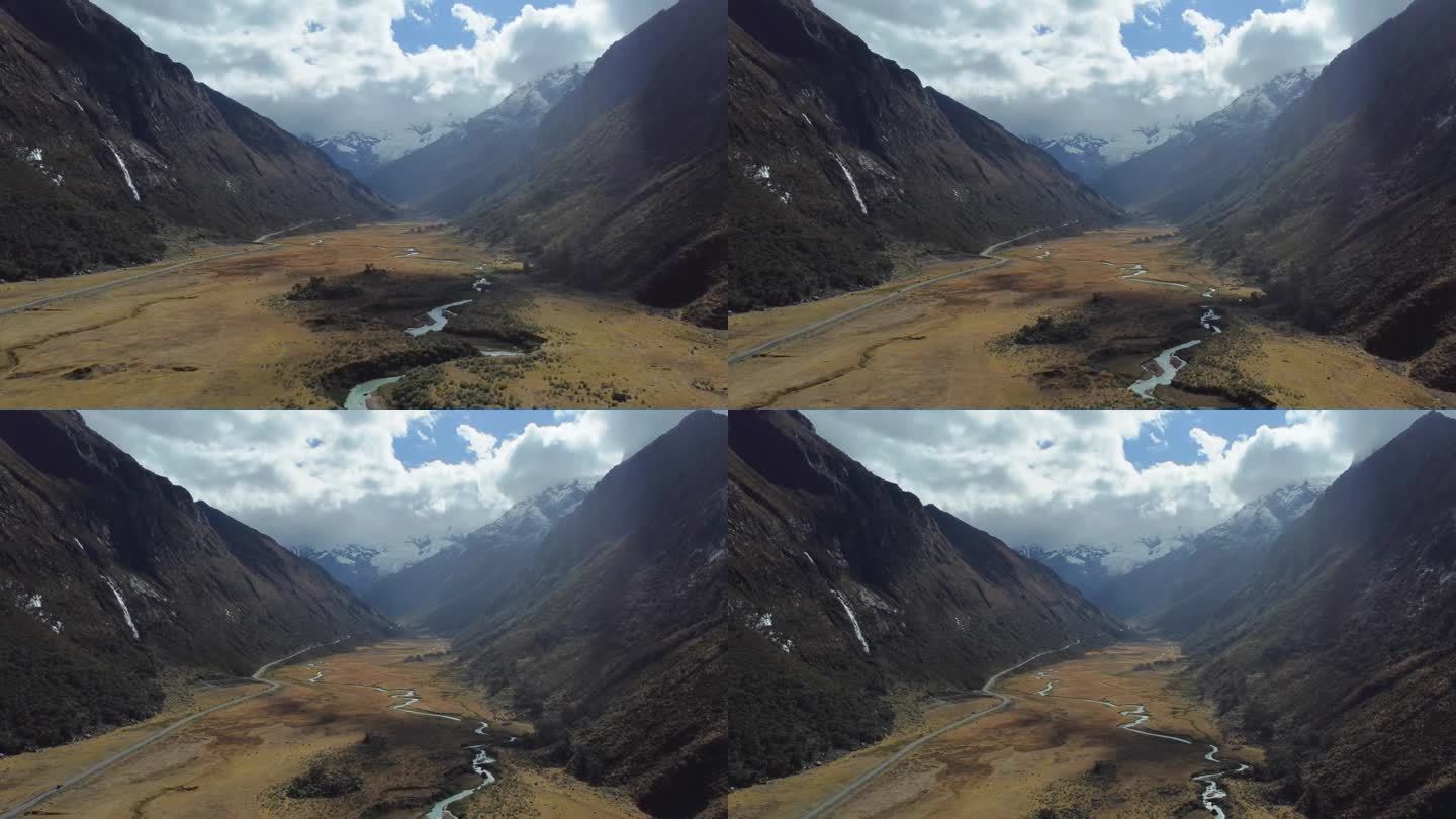 摄像机升起，小河和薄薄的柏油路蜿蜒穿过山谷，内华达马特奥山脉的山峰在阴天的远处有冰川