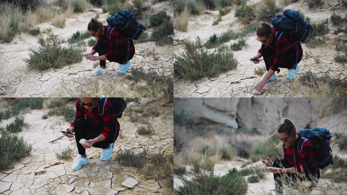 女徒步旅行者在山坡上拍摄岩石