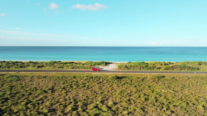 鸟瞰沿着海滩行驶的红色汽车