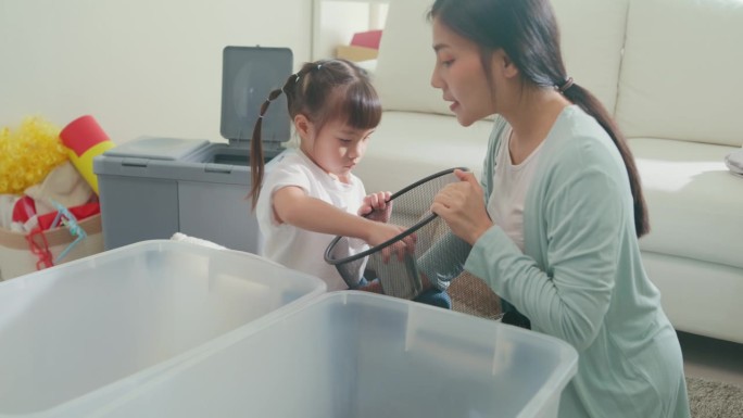 年轻的亚洲家庭妈妈教孩子如何回收帮助女孩意识到环境在家里客厅的重要性。家庭幸福时刻概念。