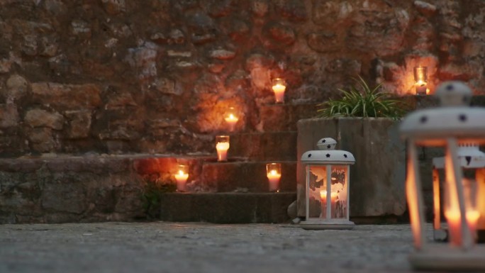 欧洲古城的台阶上放着燃烧的蜡烛。蓝色黄昏或傍晚的婚礼或招待会装饰。