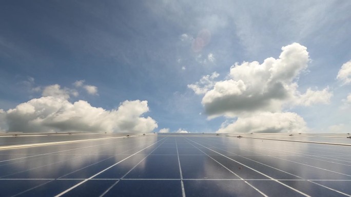 云从太阳能农场的太阳能电池板上掠过，展示了可重复使用和绿色能源的概念。