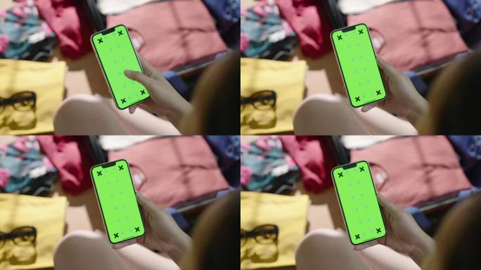 女子在打包行李时使用绿屏智能手机