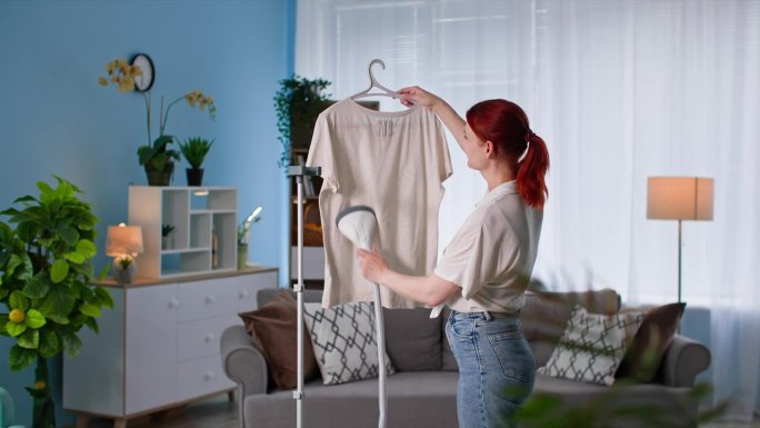 家务杂务，一位年轻女子在舒适的房间里用蒸笼和热蒸汽烫一件t恤