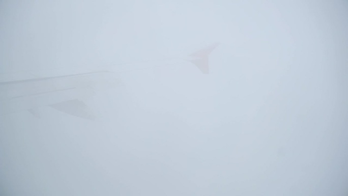 从内部看飞机机翼，在云层中飞行。