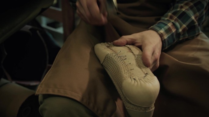 男鞋匠在私人作坊里给鞋子钉钉子。
