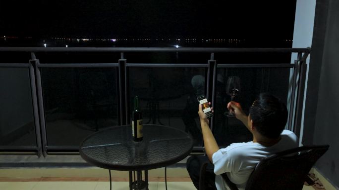 孤独的男人生活压力、阳台看手机、喝酒