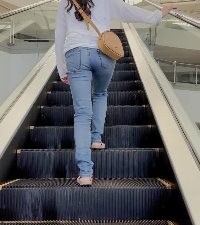 西班牙美女在购物中心爬上故障的电动楼梯