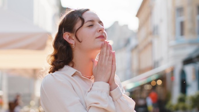 一名妇女在户外闭着眼睛向上帝祈祷，祈求祝福、帮助和宽恕
