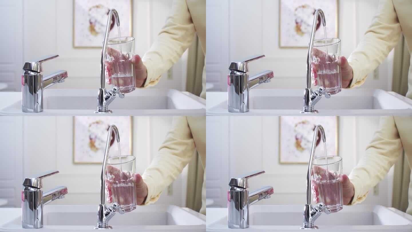 厨房里的女人用手把过滤过的水从过滤水龙头里抽到玻璃杯里。过滤龙头在中间，中拍，4k